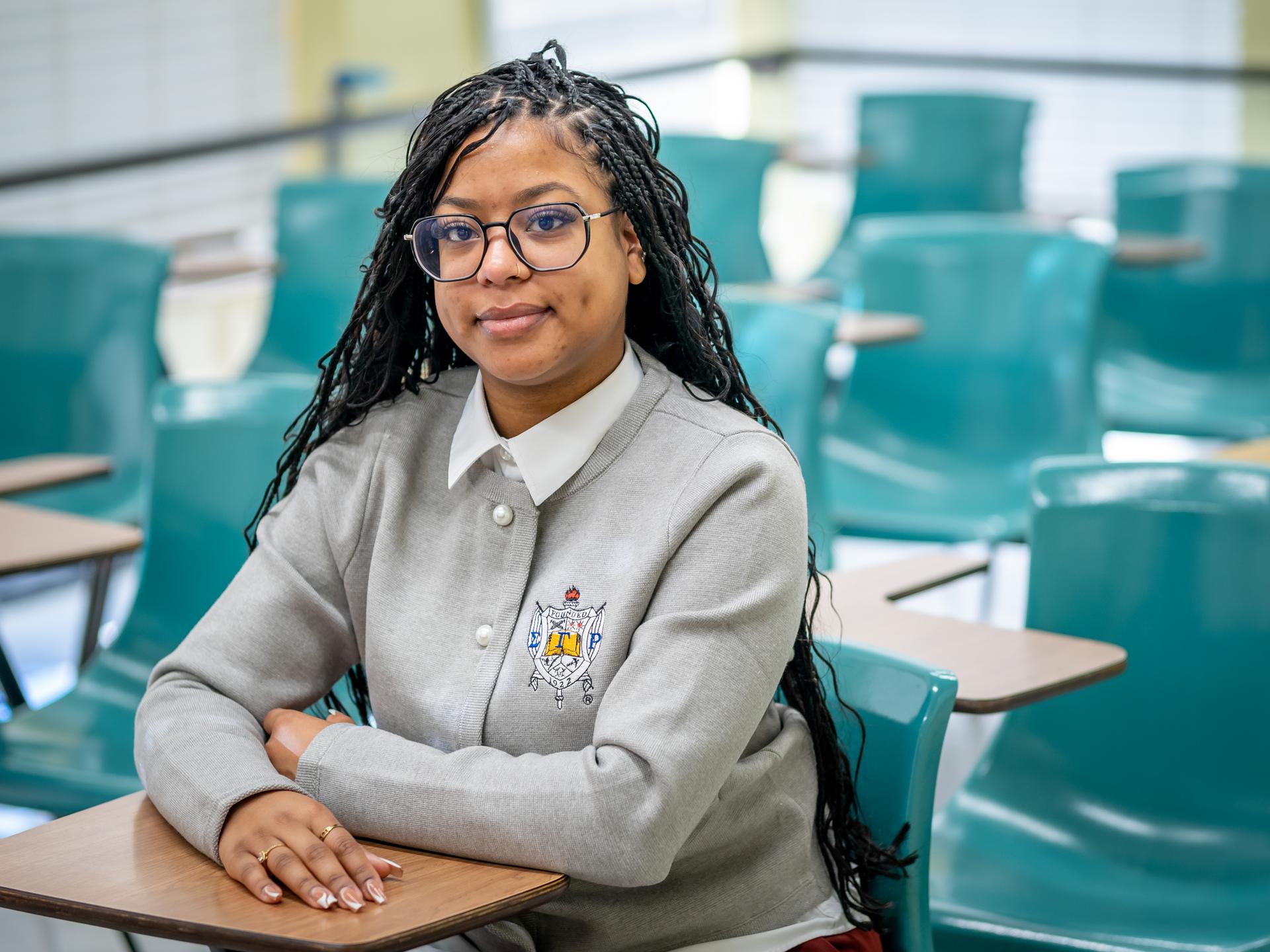 Lisha Brito sitting in a classroom, posing for a photo.