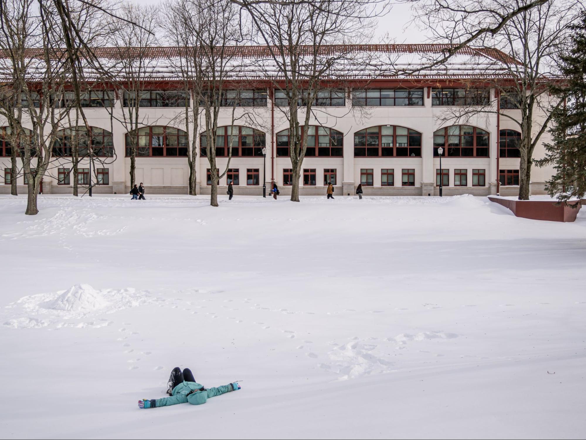 A photo of a student laying in the snow on Montclair's Campus