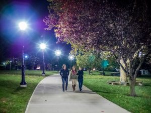 Photo of students walking on path lit by streetlamps
