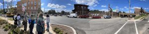 a wide lens image of students standing on a corner in Orange, NJ with the train station in the background. 