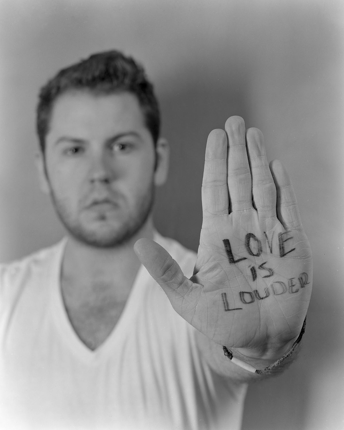 Man holding up hand with "Love is Louder" written on his palm.