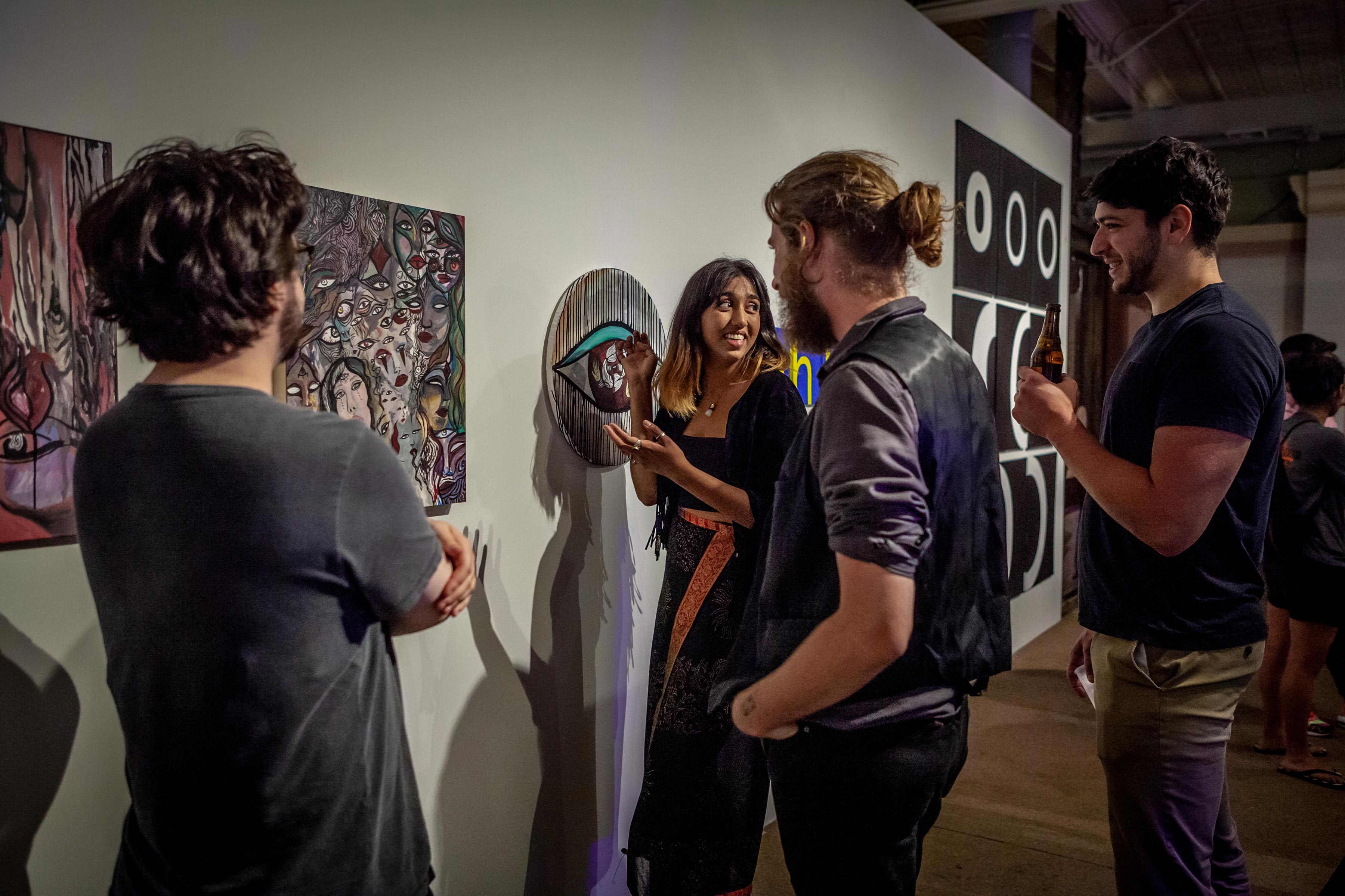Student artist discusses her work with three attendees