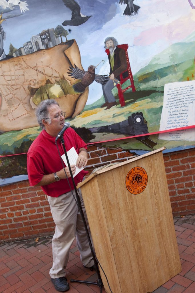 man speaking in front of mural