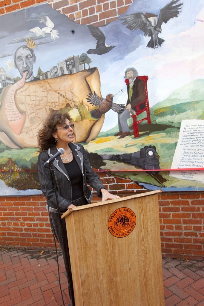 woman speaking in front of mural