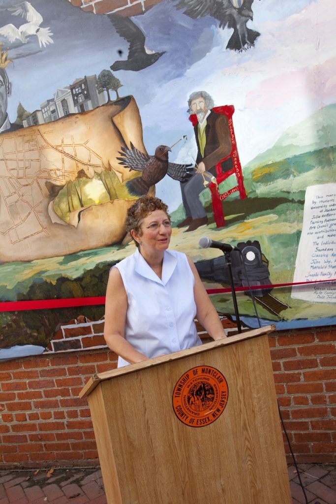 woman making speech in front of mural