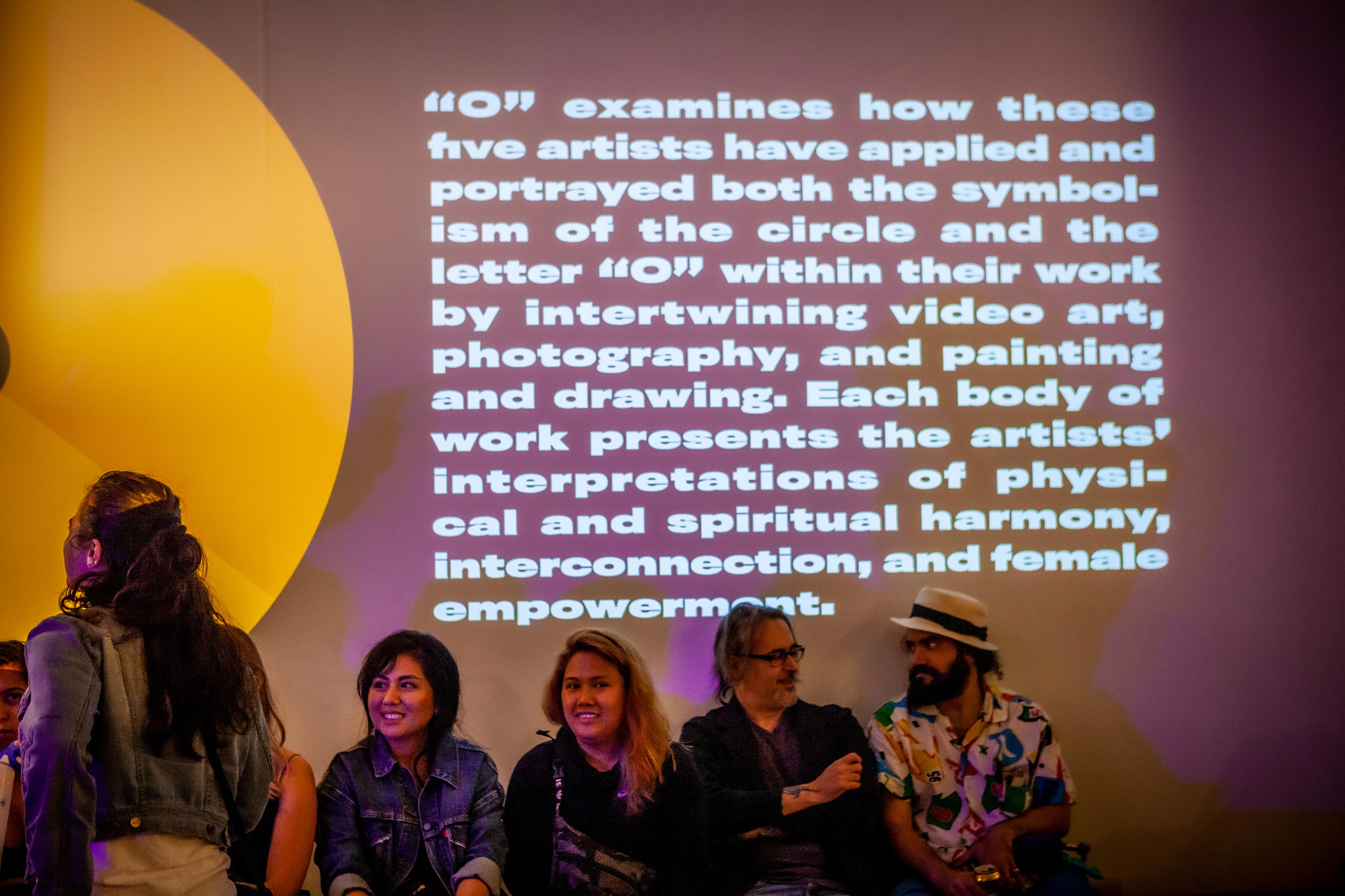 group of guests sitting against wall with paragraph of text projected onto it