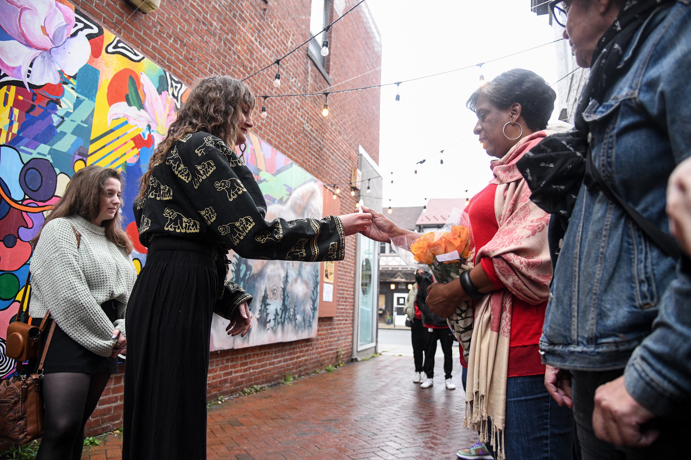 Artist Lauren Vroegindewey gives Norma Tassy the pen to write the name of her son, Jordan, on the mural
