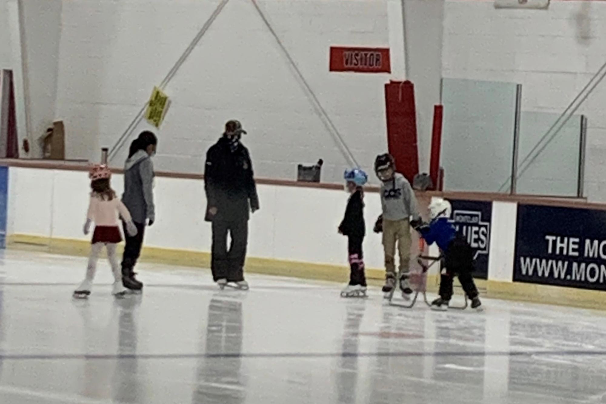 Children learning to ice skate at the ice rink.