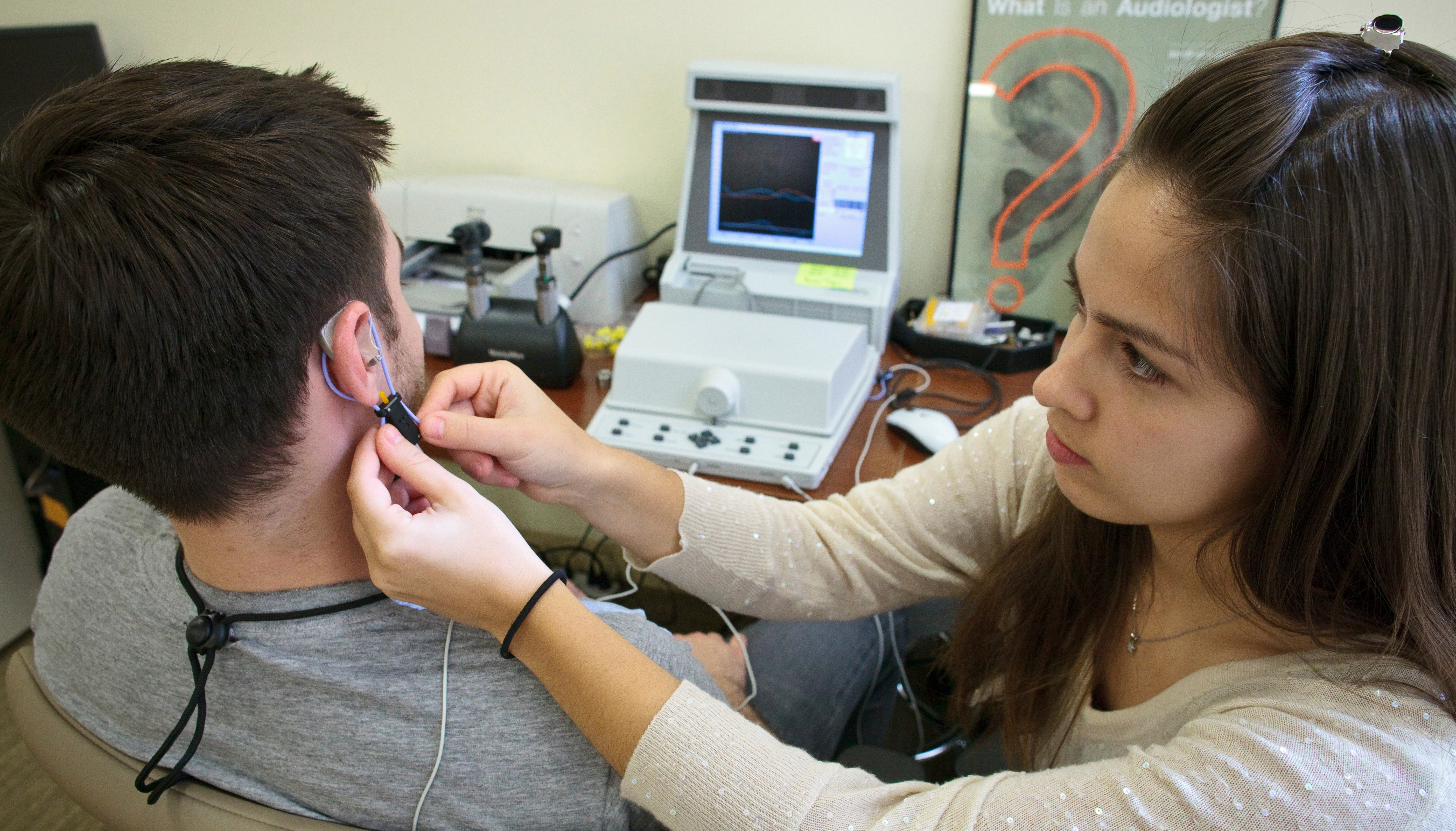 Woman assisting man with hearing device