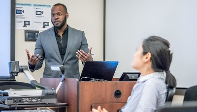 Man lecturing at podium while woman listens