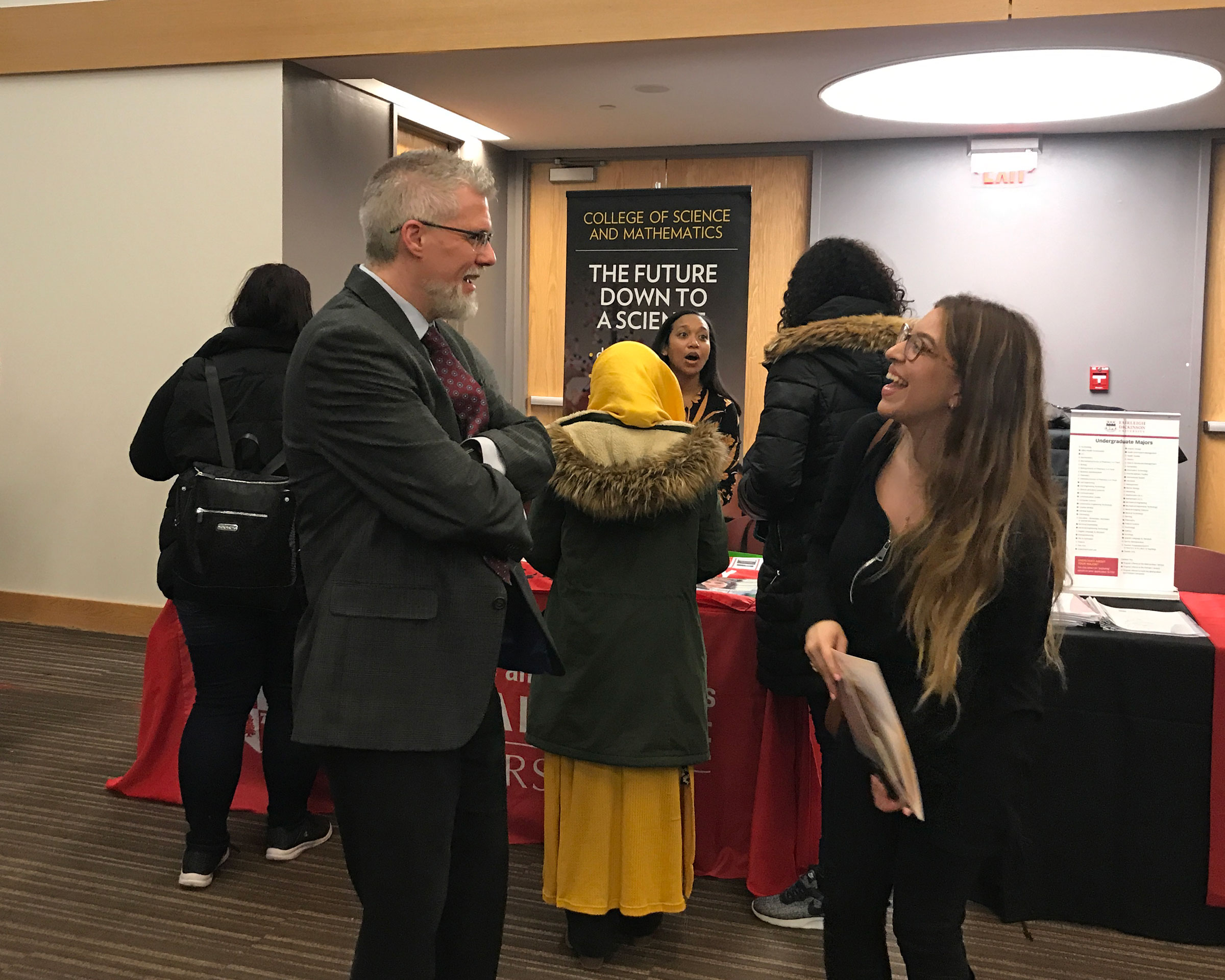 Faculty and staff talking with students at the University's booth