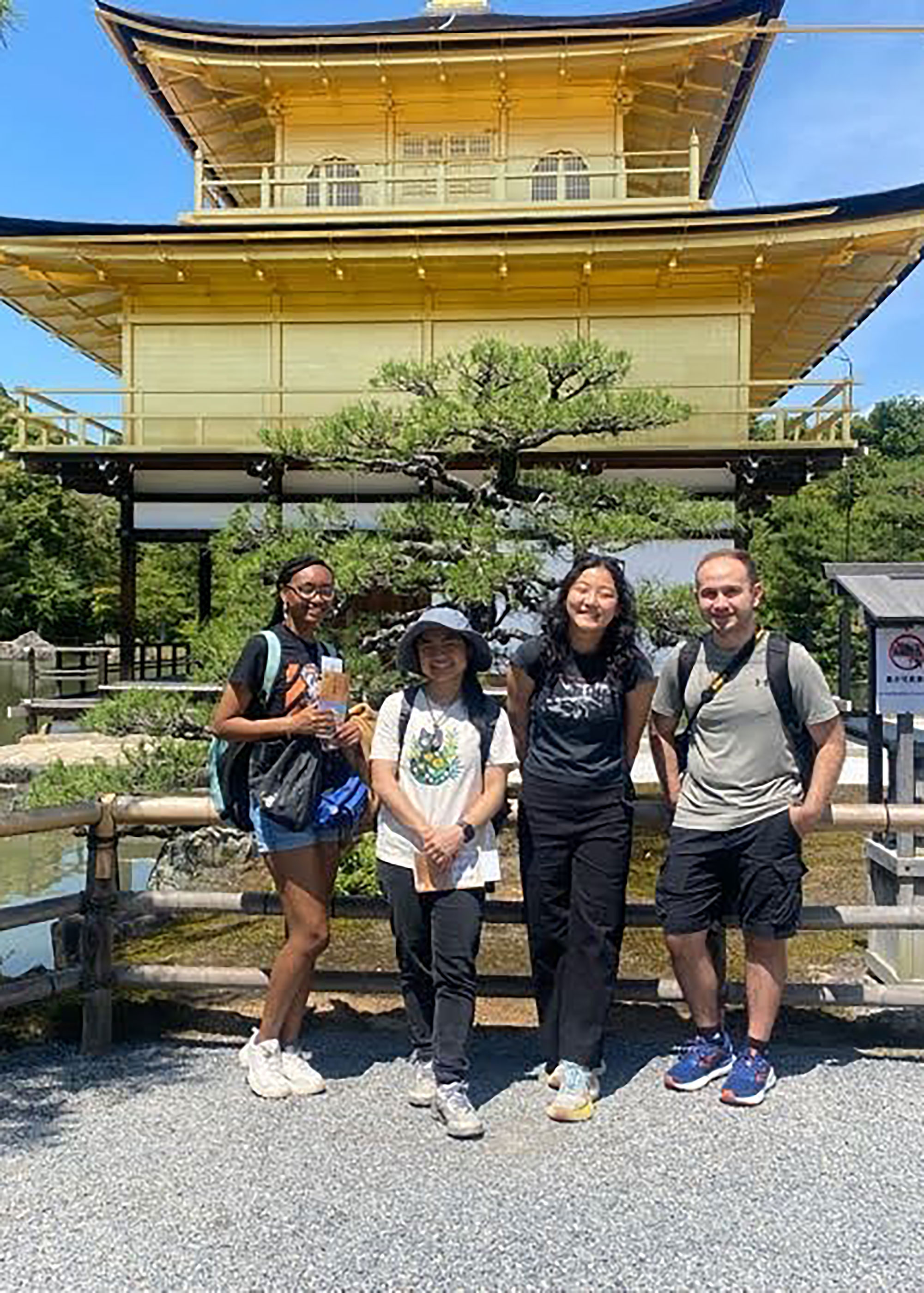 group in front of bonsai tree and building