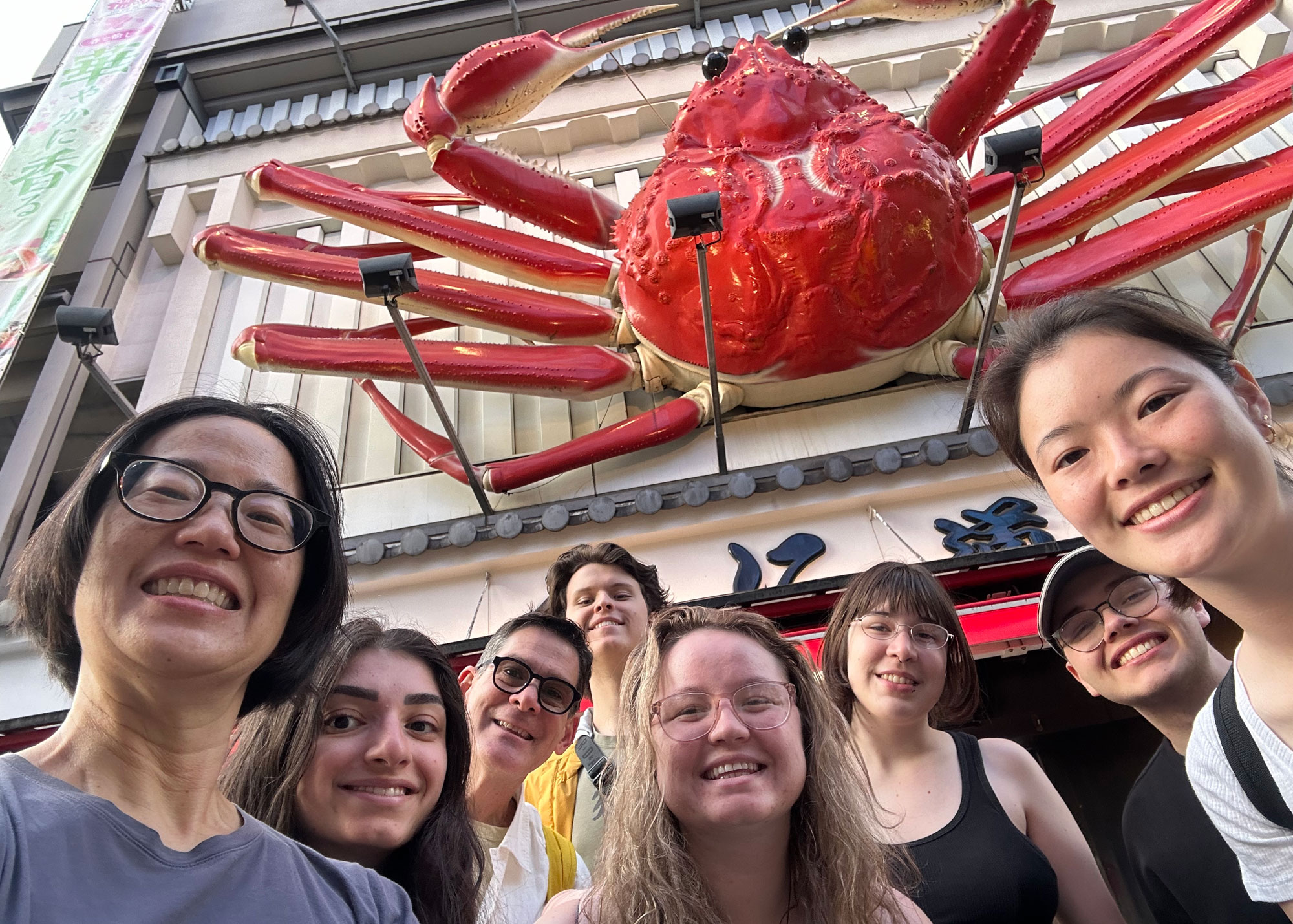 group outside sushi restaurant, large crab sign