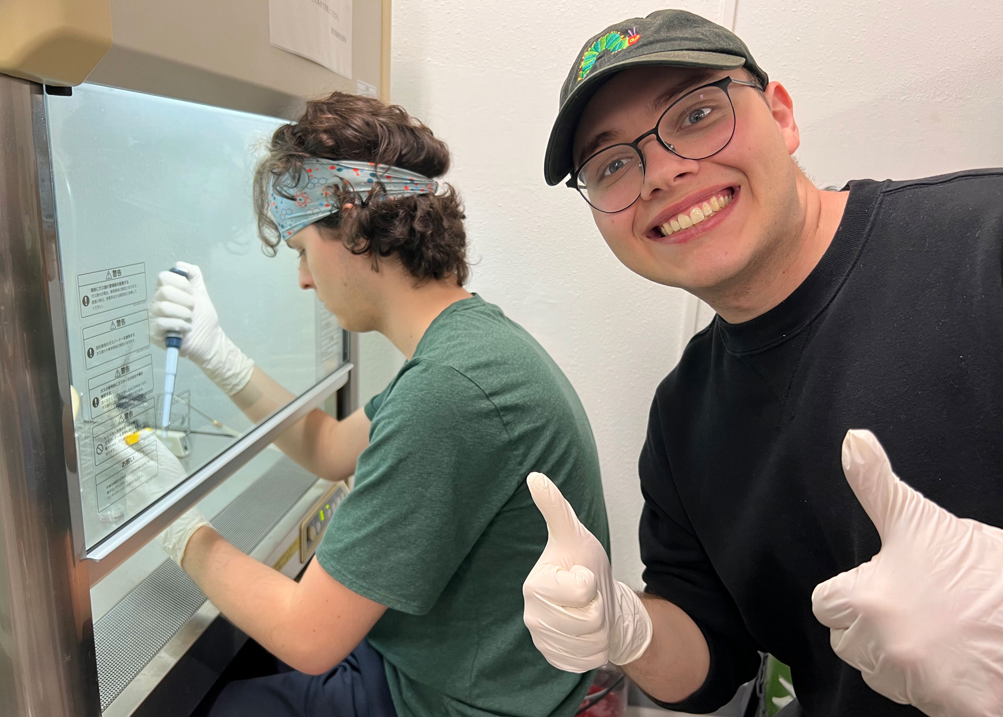 student working in hood with colleague photobomb