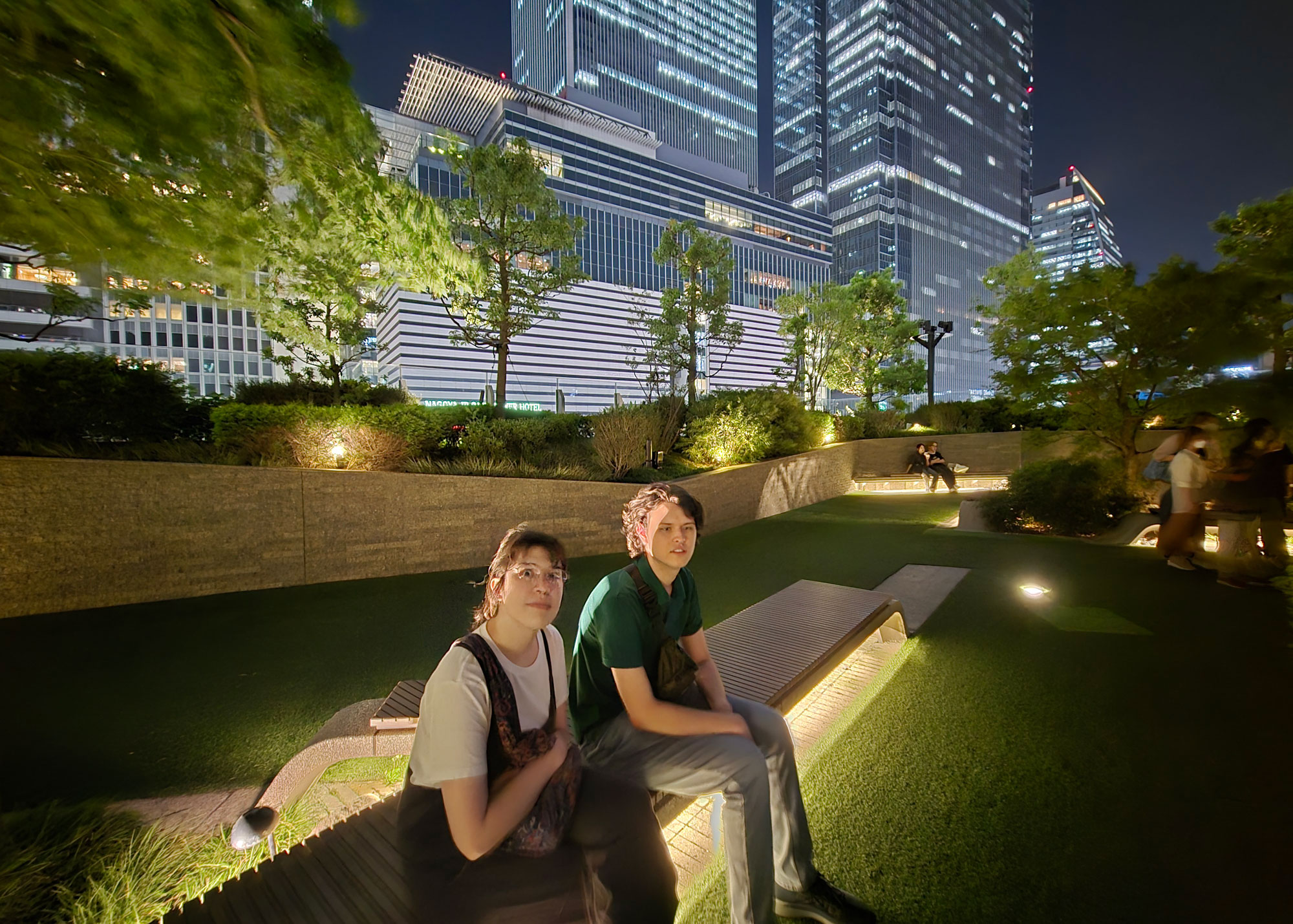students sitting on bench at park at night