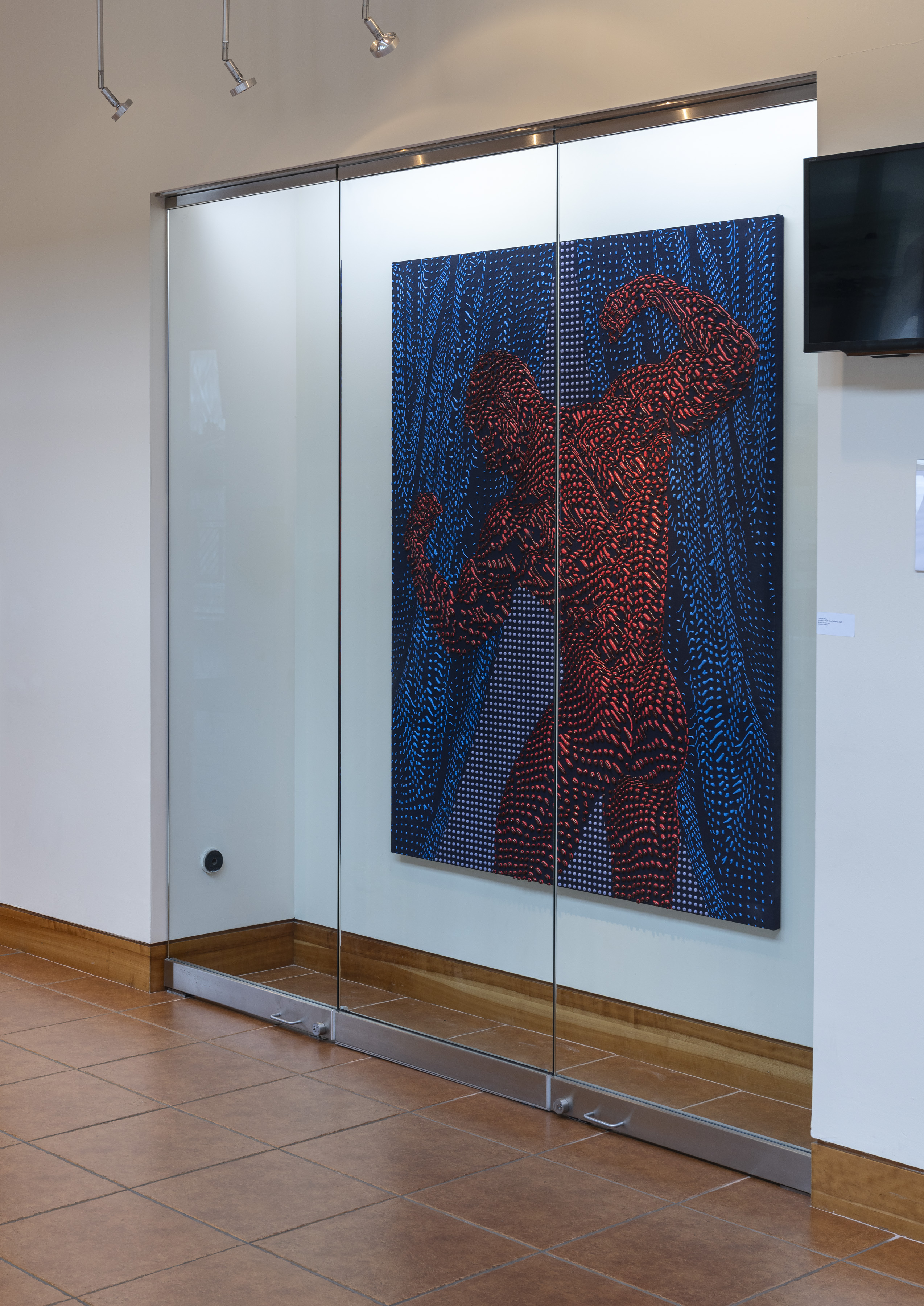 Installation image of a navy blue and red painting behind glass.
