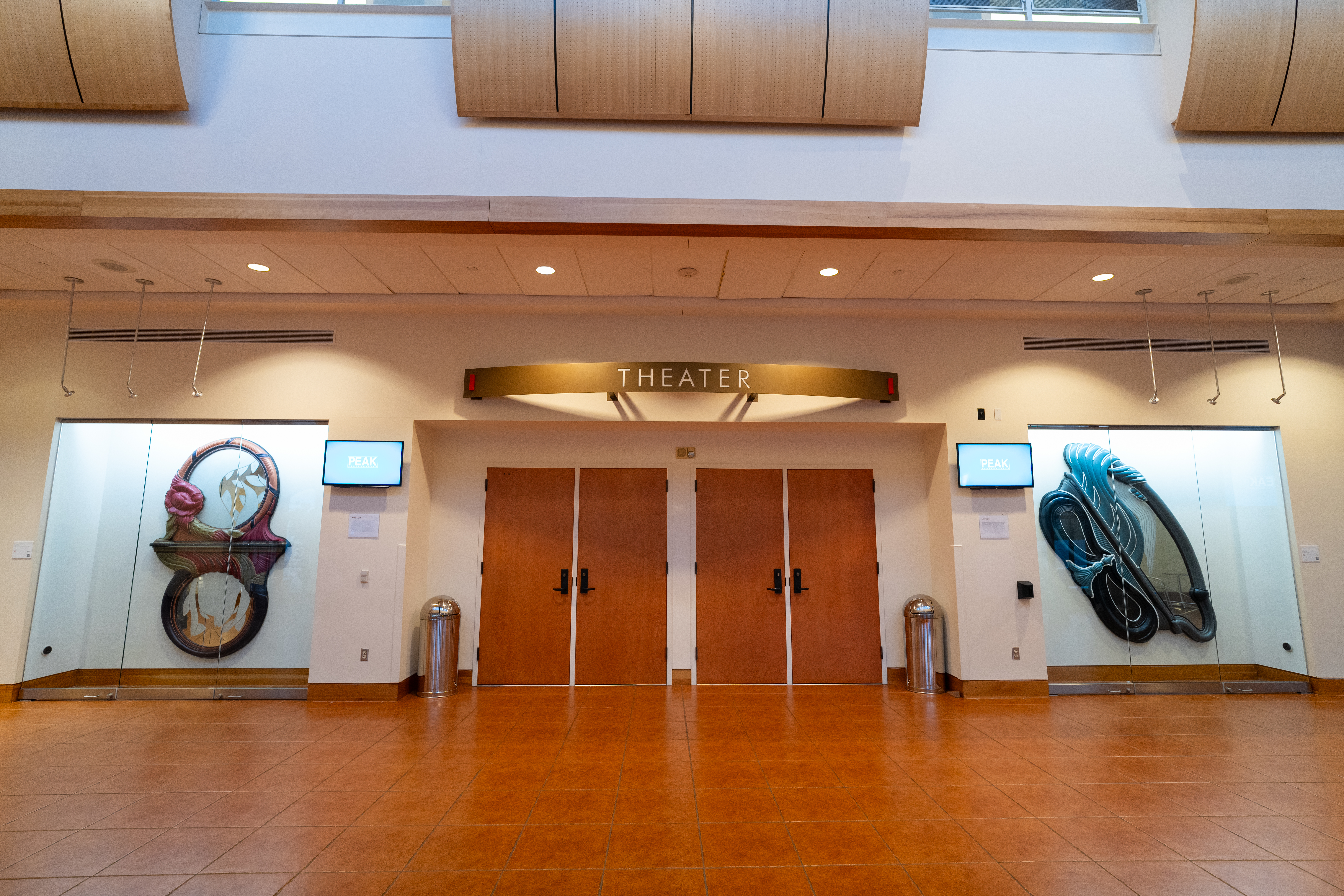 Two large artworks in separate glass cases in the lobby of the Kasser Theater.