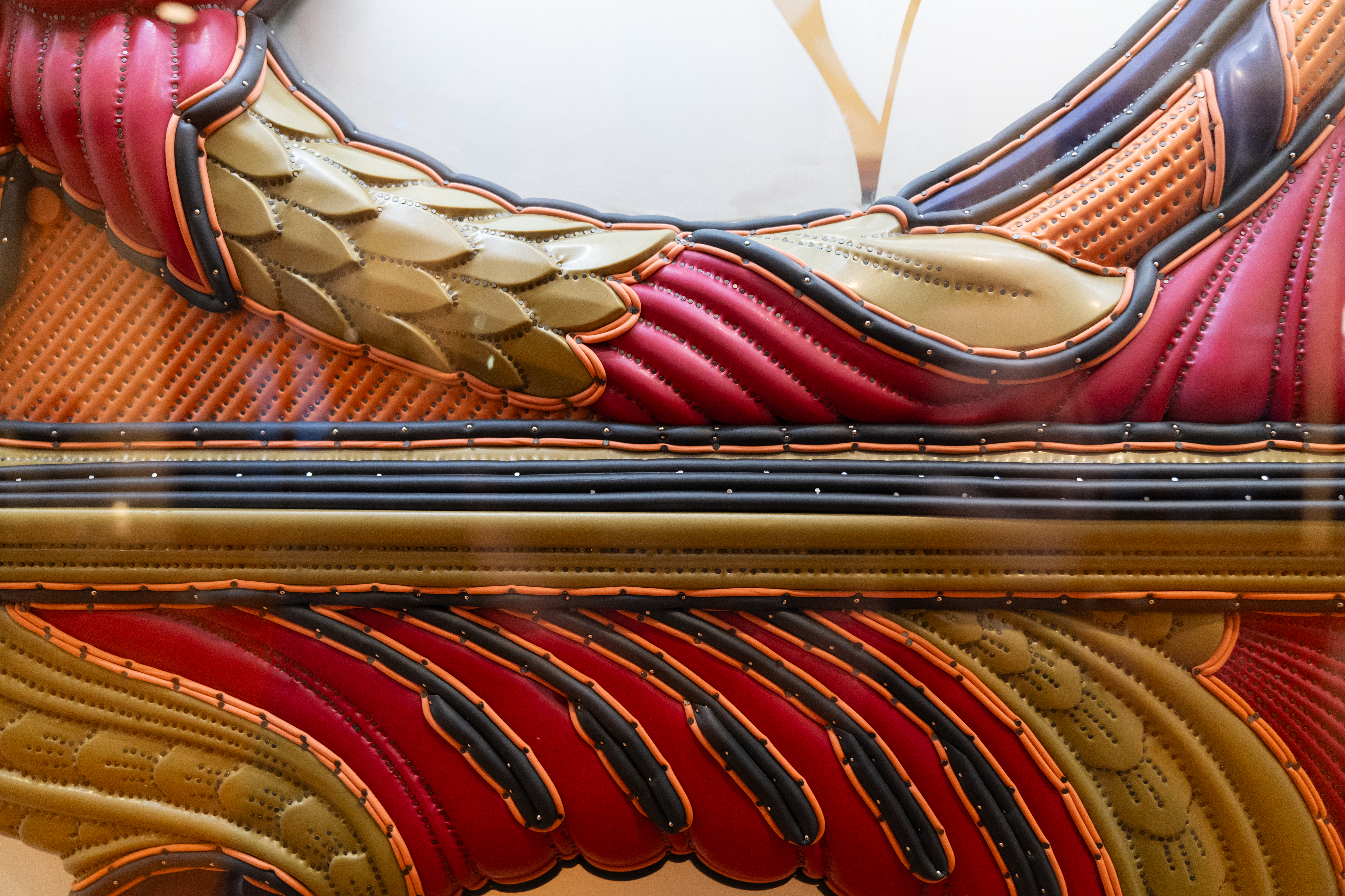 Close up of an artwork that features the colors maroon, olive, orange, and black.