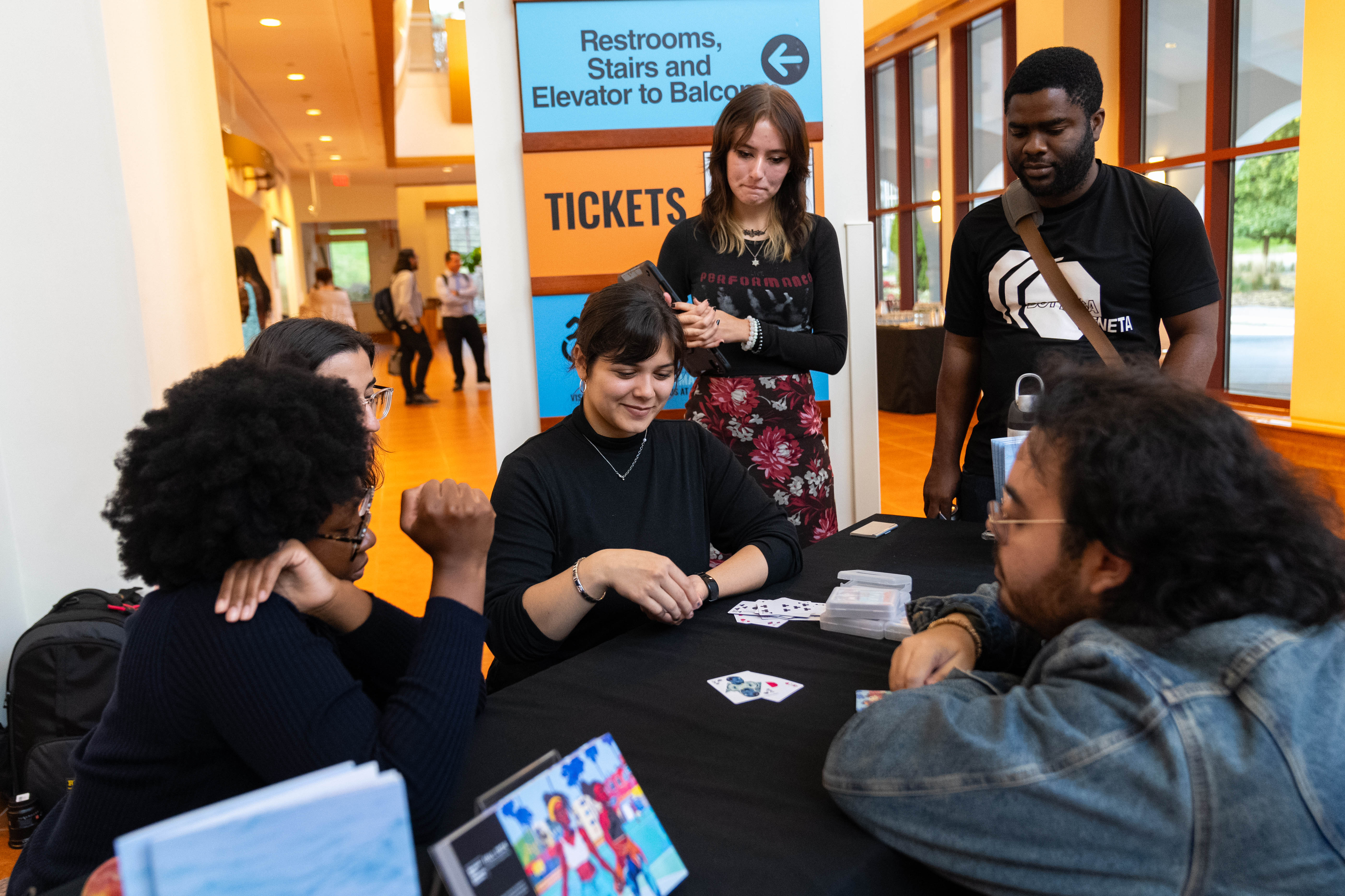 Students play a game of cards as part of a social engagement-based performance piece.