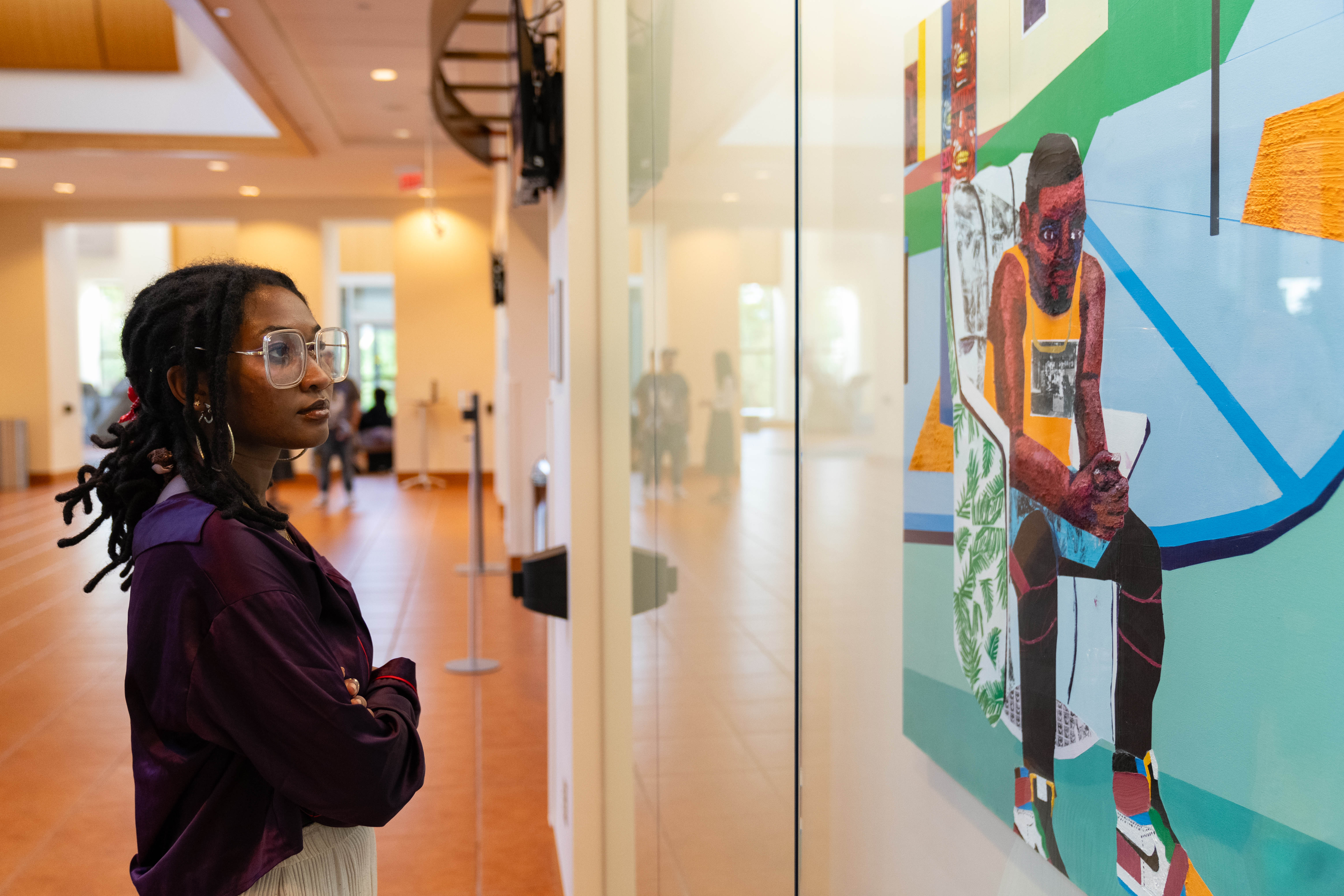 A visitor stares at a painting of a figure behind glass.