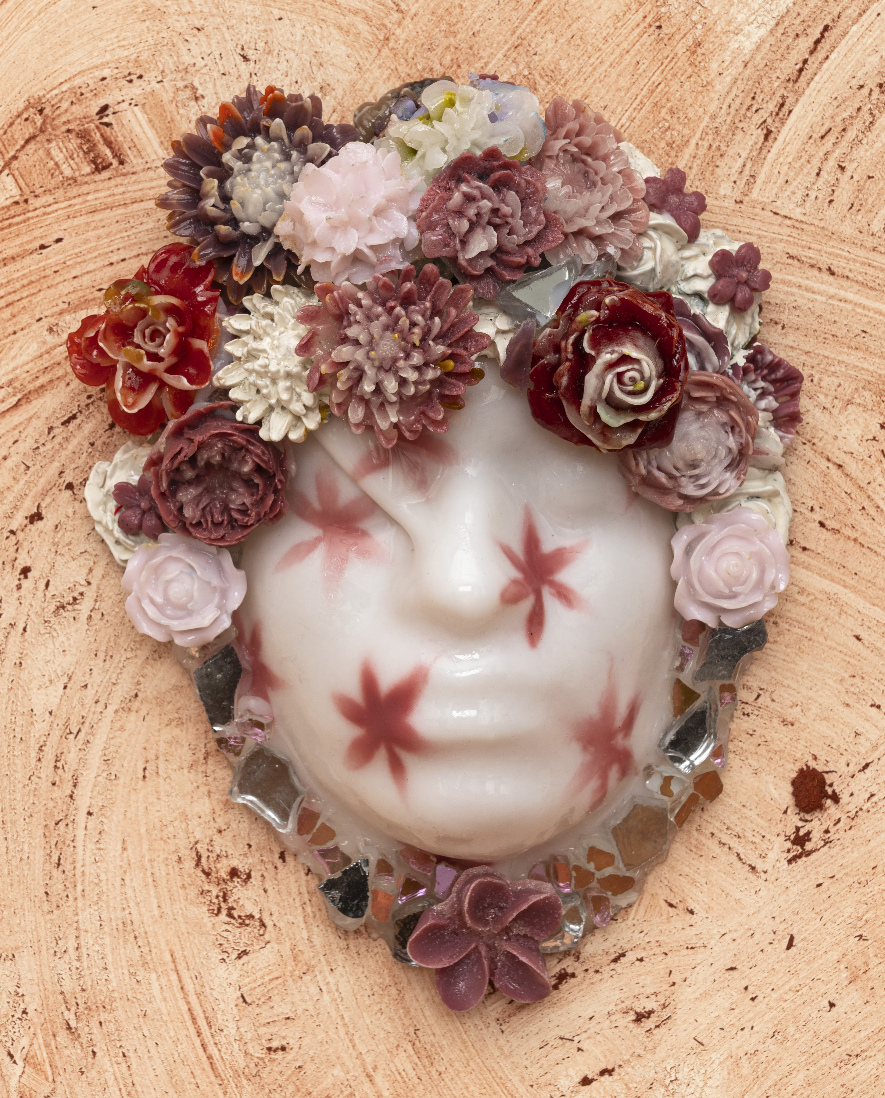 Close-up of glass portrait against a dusty pink wall. The glass is milky white and is stamped with rose-colored flowers.