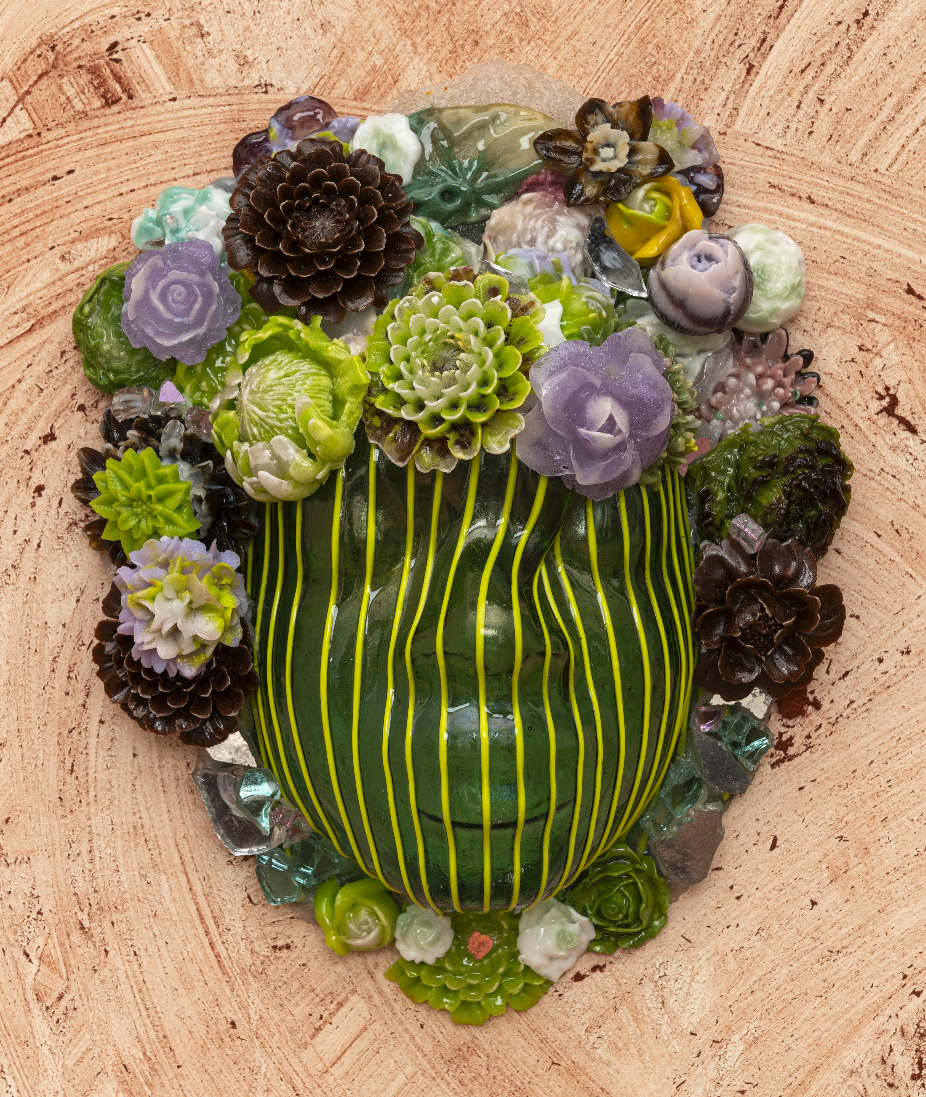 Close-up of glass portrait against a dusty pink wall. The glass is dark green, with light green stripes.