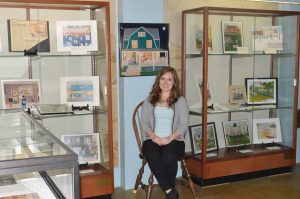 Image of Torri Brouhard sitting with paintings from a museum collection.