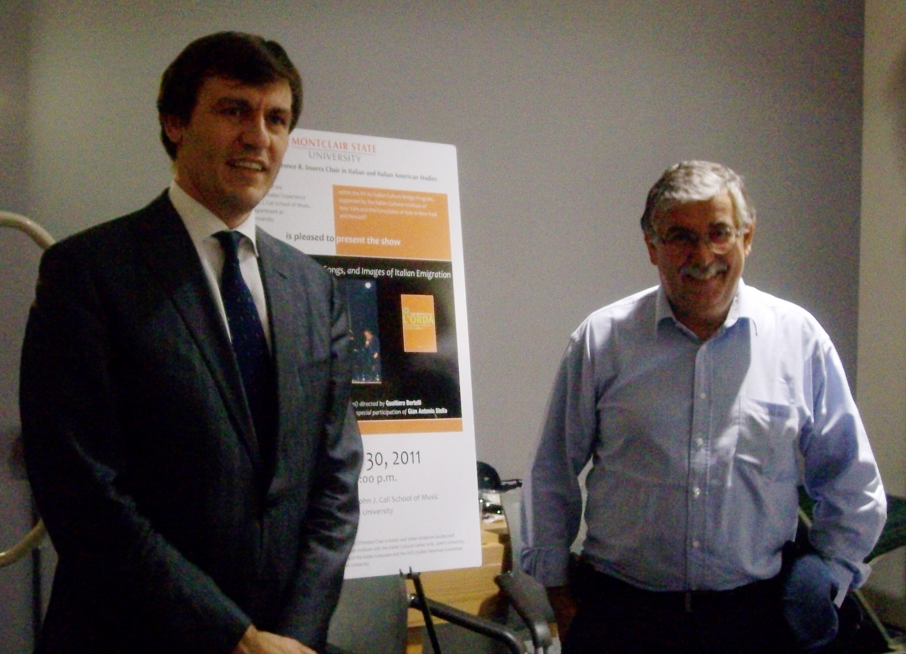 two men posing with event poster