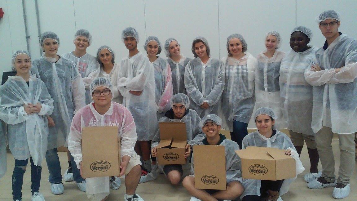 Large group of high school students wearing protective plastic clothing get an inside look on how a Italian packaging plant works