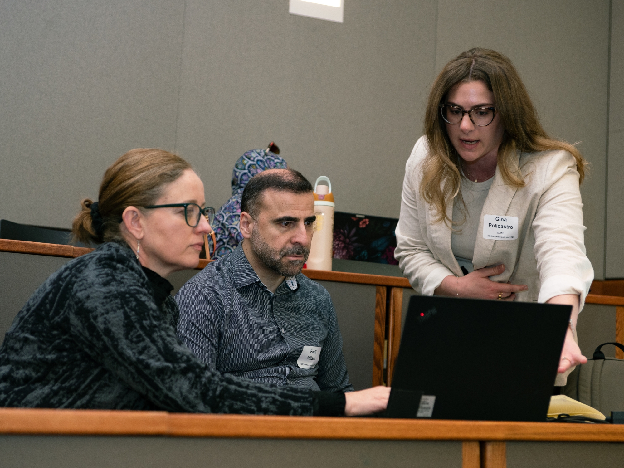 Two people helping a person on a laptop.