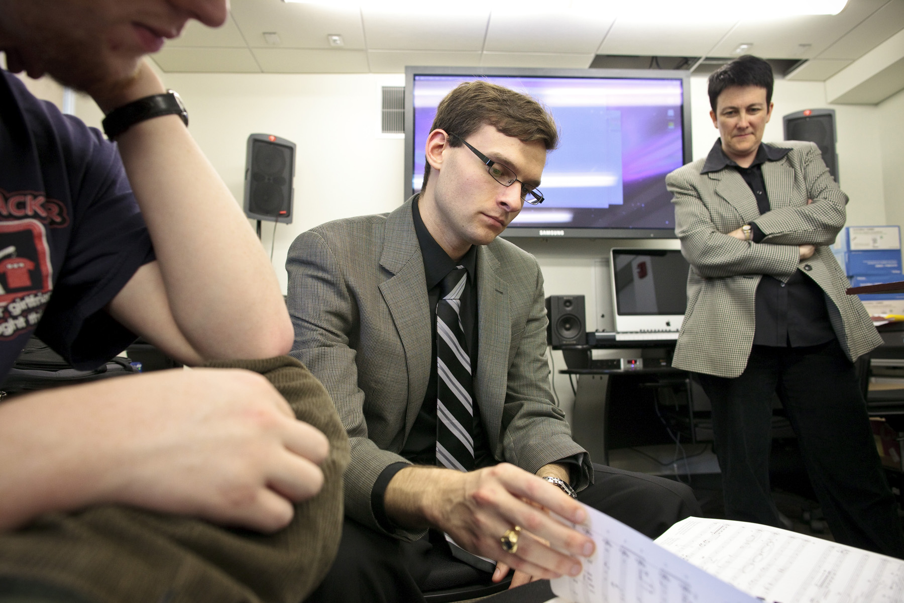 Composition student, Nathaniel Liberty (center) follows along in the score as they listen to "Zaka."