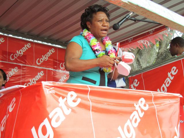 Rose Andrew, a dentist from Papua New Guinea, talking into a microphone making a speech.