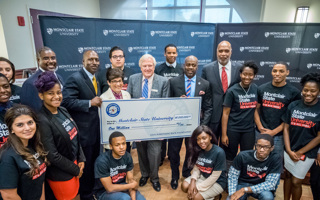 Dr. Susan Cole and GSBF Founder Robert Carr, surrounded by students, holding giant check for $1 million. 