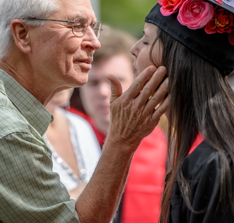 Father giving his graduating daughter a kiss.