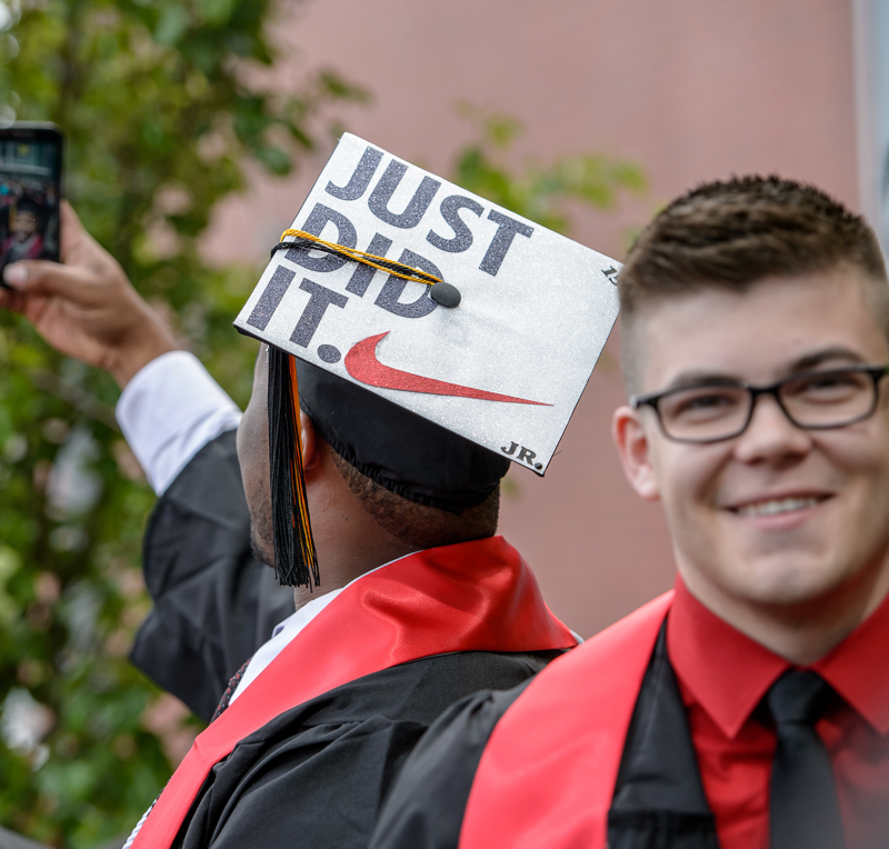 Montclair State University student wearing a graduation cap that says "Just Did It" alongside the Nike swoosh taking a selfie.