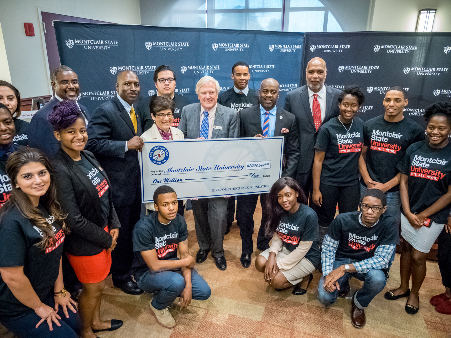 Dr. Susan Cole and GSBF Founder Robert Carr, surrounded by students, holding giant check for $1 million.