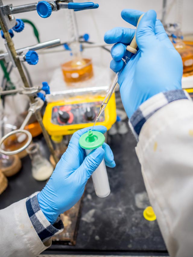 Photo of pipette dispensing solution into a test container from the researcher's point of view.