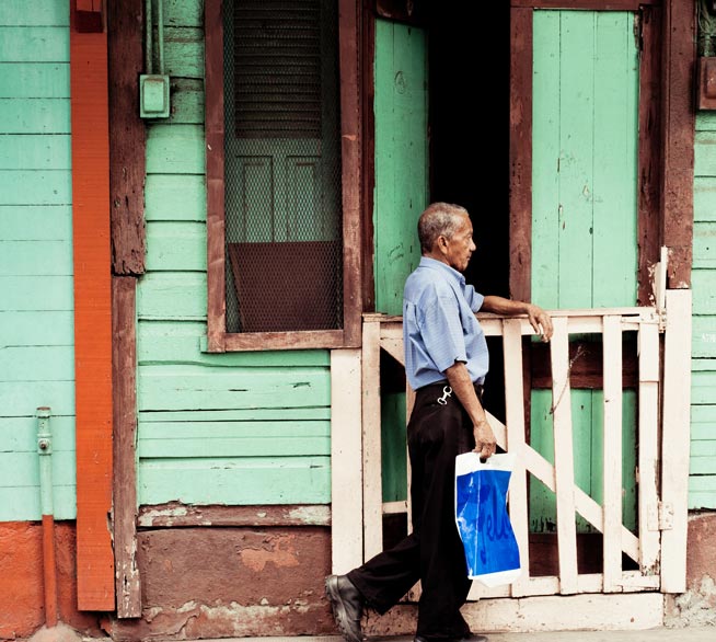 Photo of a man walking in front of a wooden-gated doorway