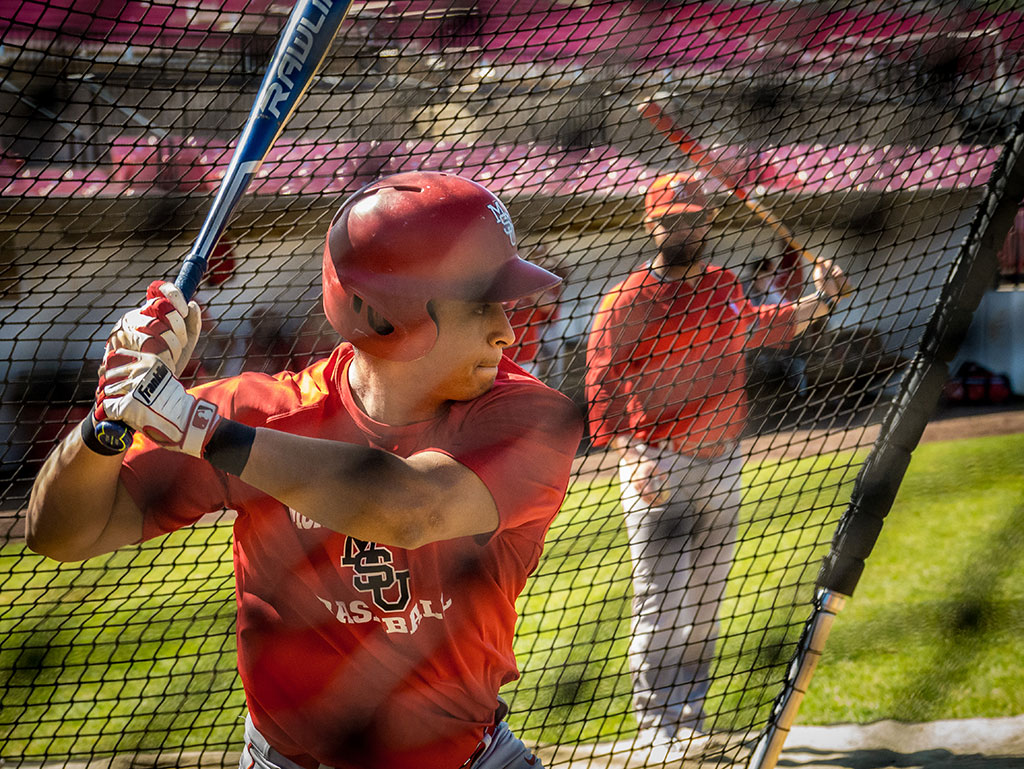 Jesse Baiza swinging baseball bat in batting cage.