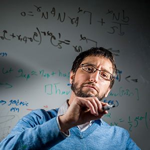 Photo of Marc Favata writing equations on glass.