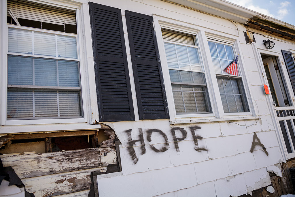 Photo of rundown house with the word "Hope" written on front of it.