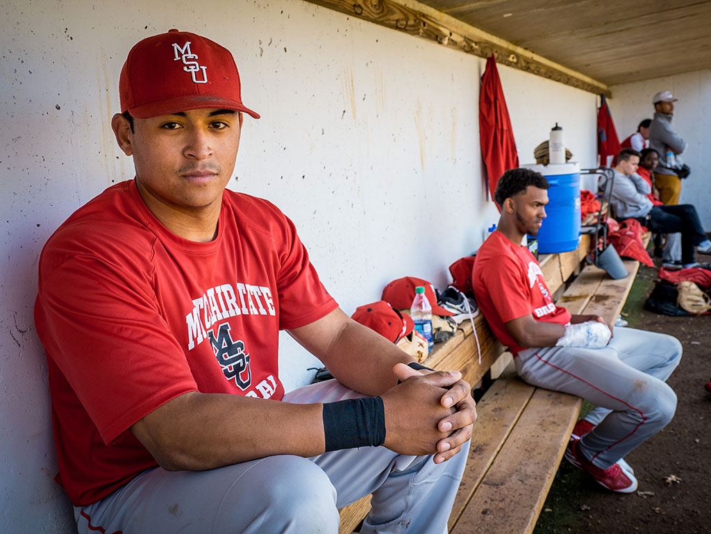 Jesse Baiza sitting in dugout with teammates.