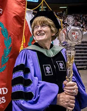 Photo of Domenica Desiderioscioli, clad in Commencement gown and holding scepter.