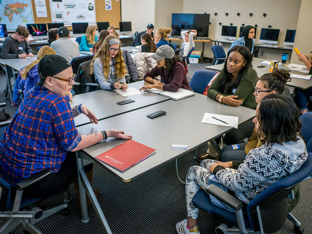 Students sitting around table helping in human rights workshop.