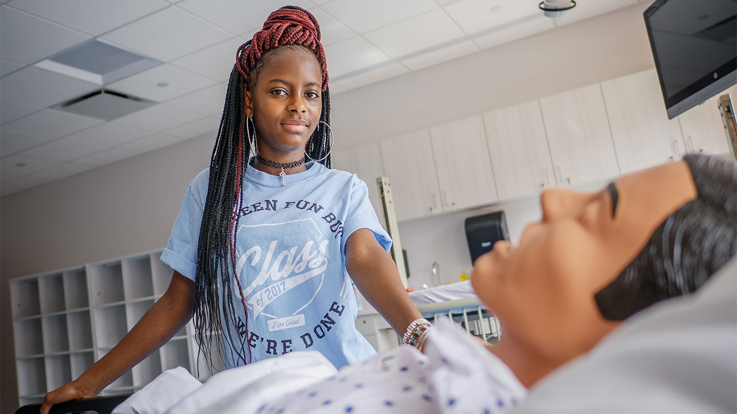 Rokia Fane, freshman in the four-year BSN class, posing with nursing dummy.