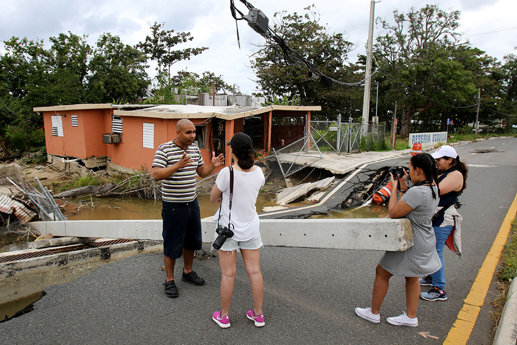 A man in Boquerón, Puerto Rico, talks with Obando, De La Rosa and Garcia about the tsunami-like storm surge that occurred during Hurricane Maria, destroying his grandparents home behind him.