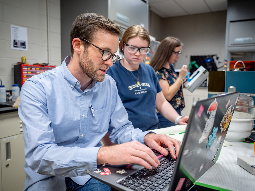 O’Neil works on chemistry experiments with senior Kelly Obrzut (center) and junior Katherine Schaffer (right) in his lab. Schaffer is part of the team working to create tools to measure neurotransmitter pathways.