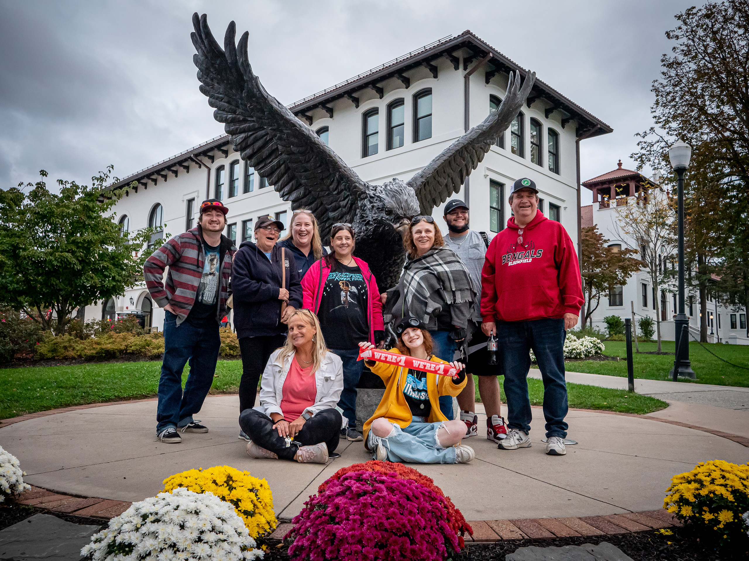 alumni and their families posing at the hawk statue on campus