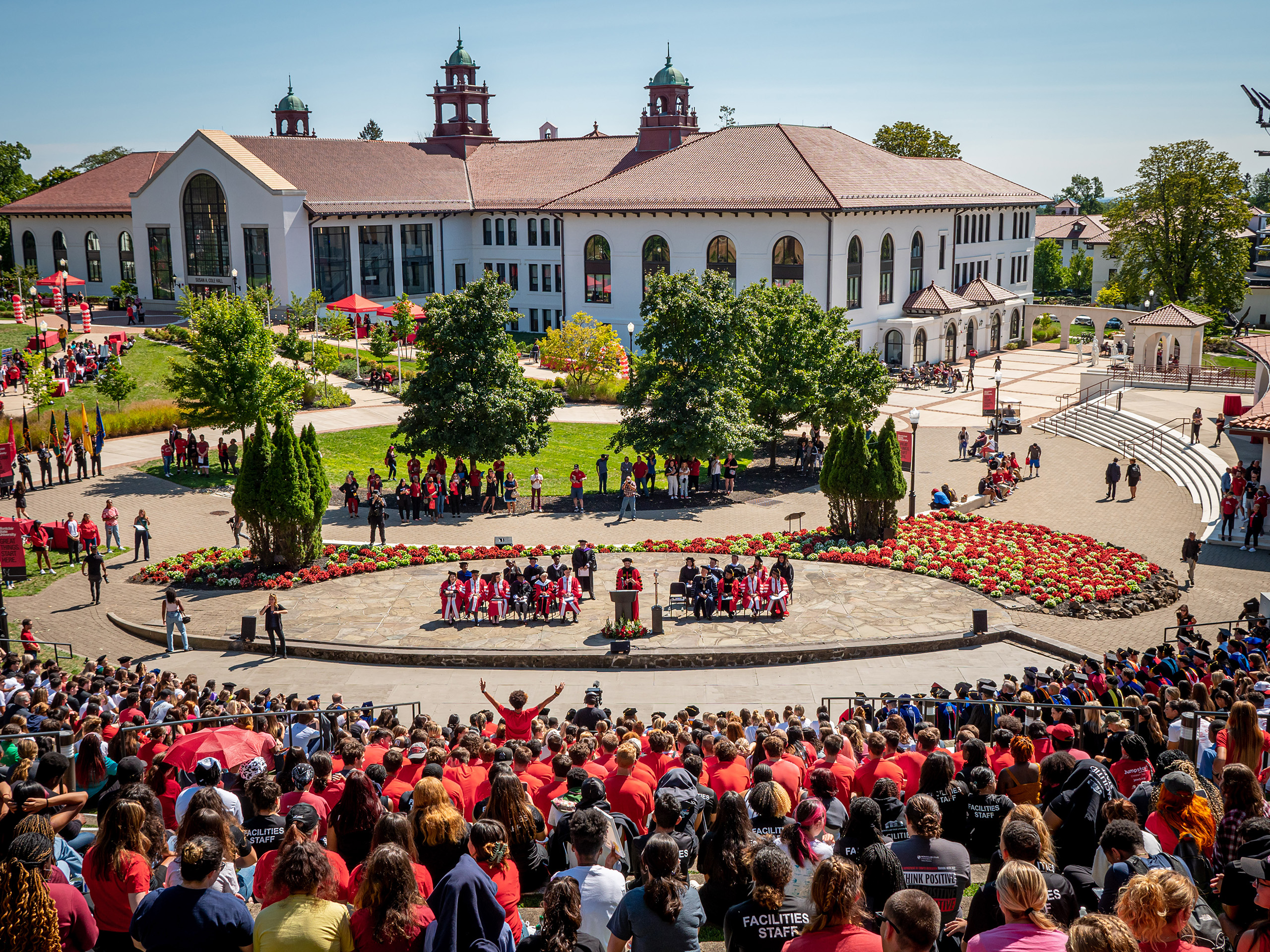 President Koppell speaks at podium in front of attendees seated in outdoor amphitheater on campus