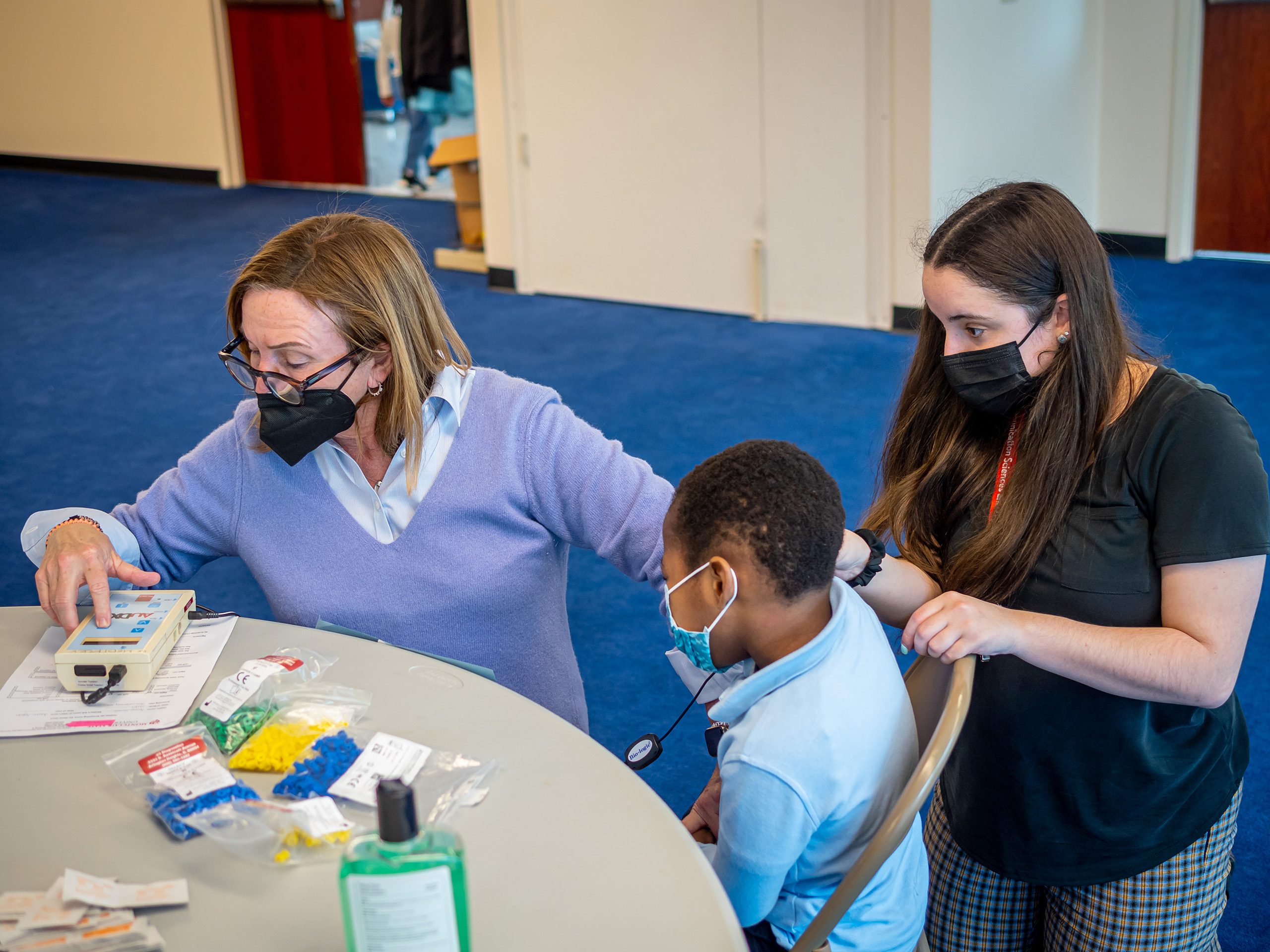 Professor Maryrose McInerney and student Alyssa Bonapace seated at a table with young student in Newark.